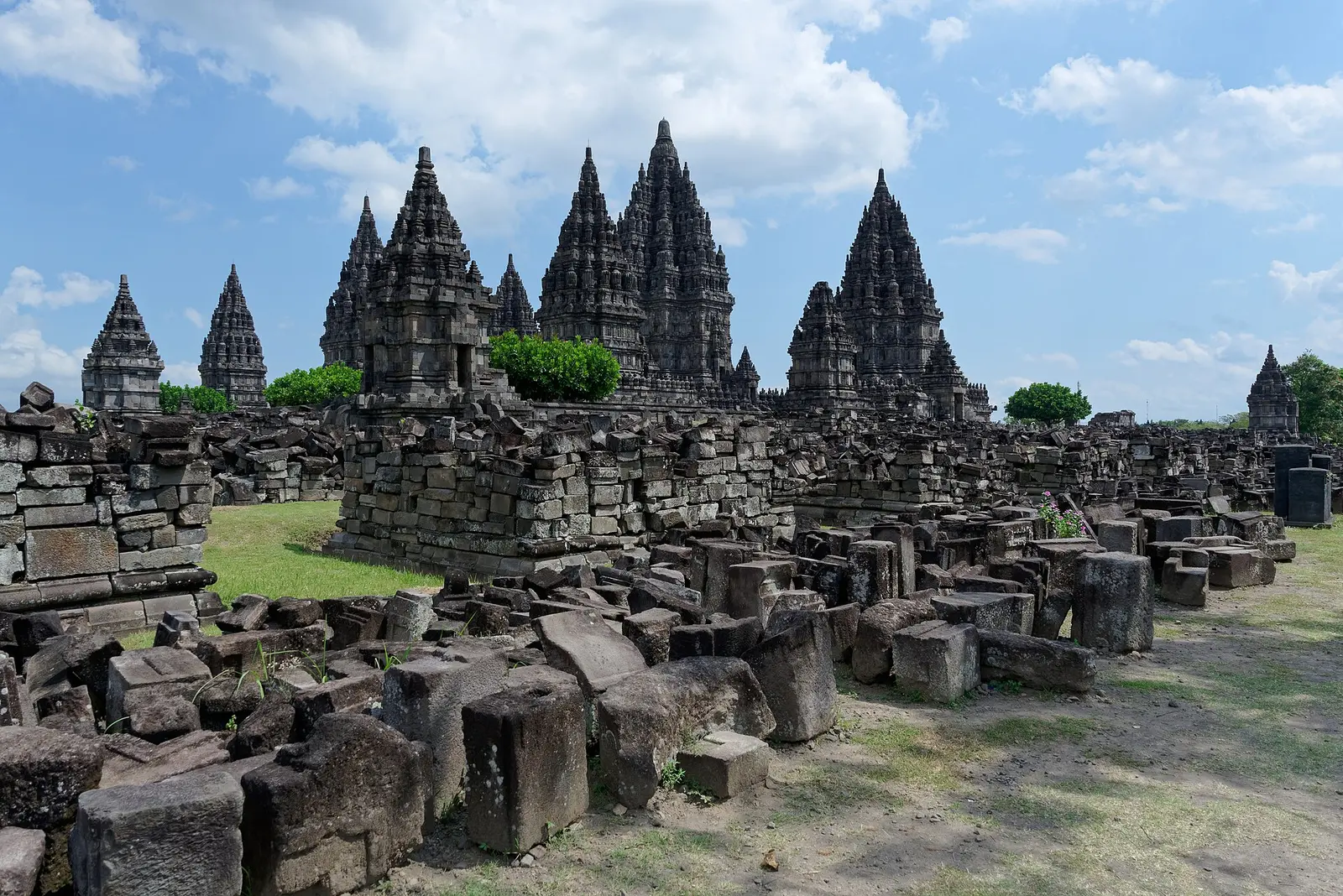 Prambanan temple towers rising above stone ruins under blue sky